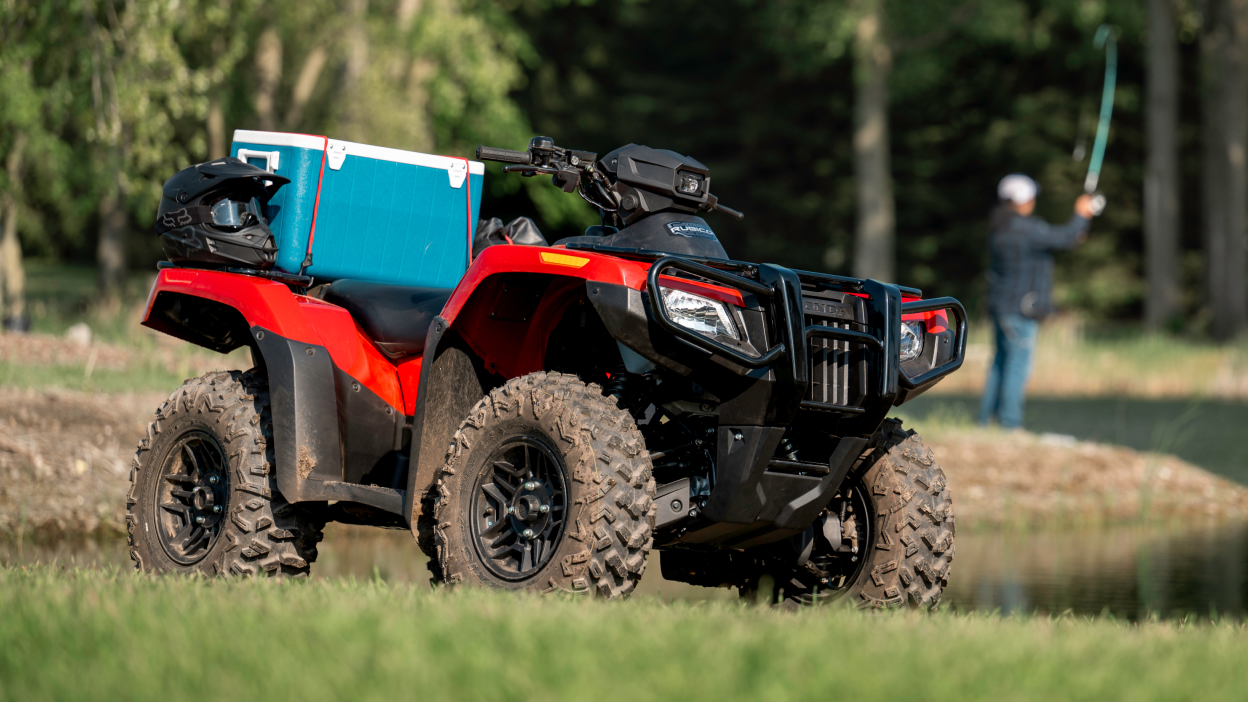 Rubicon stationary with blue luggage on back. Person fishing in background.
