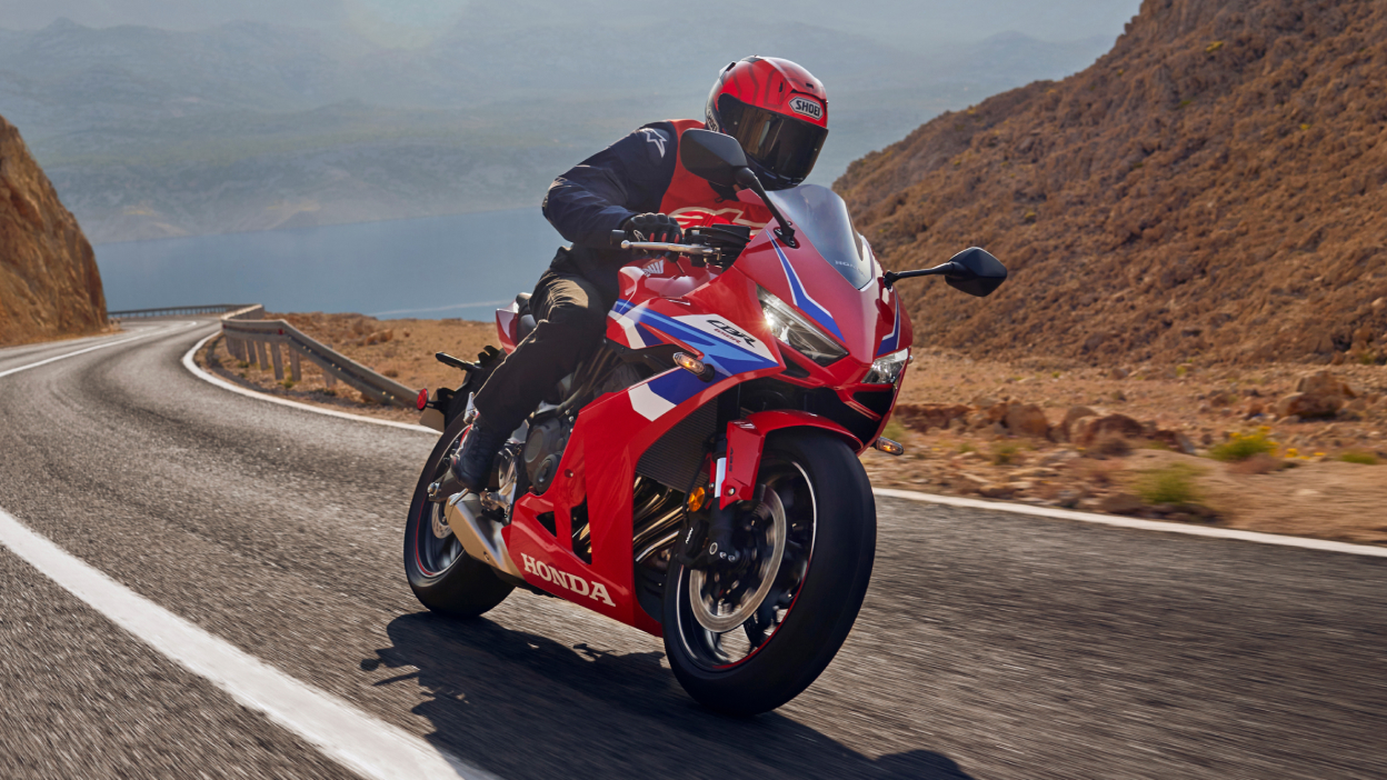 Rider on CBR650R E-Clutch going right on road. Rocky landscape in background.
