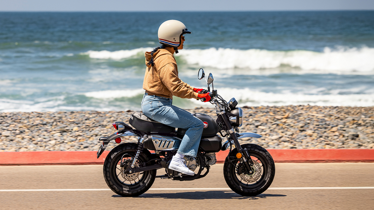 Rider on Motorbike going right on road. Beach in background.